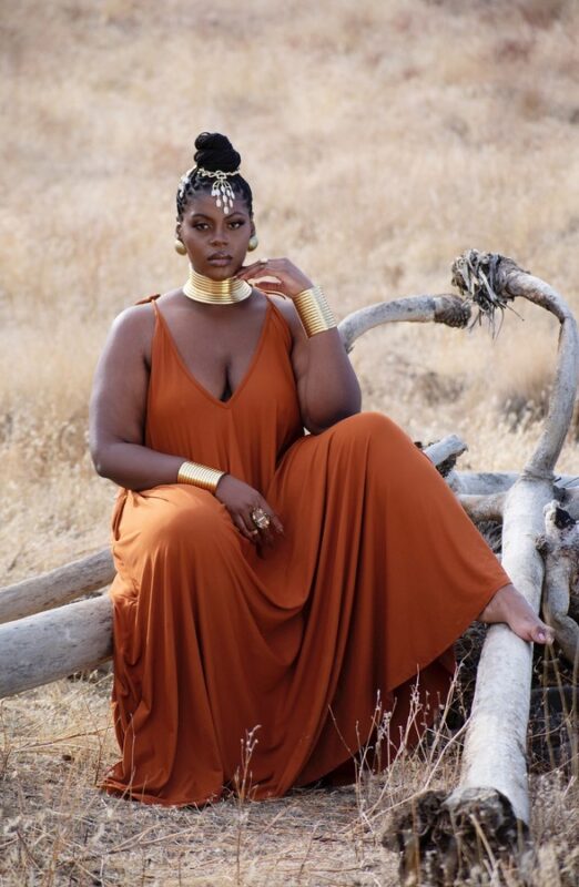 Tribal woman in the wilderness in a brown maxi dress with gold metal choker and bracelets